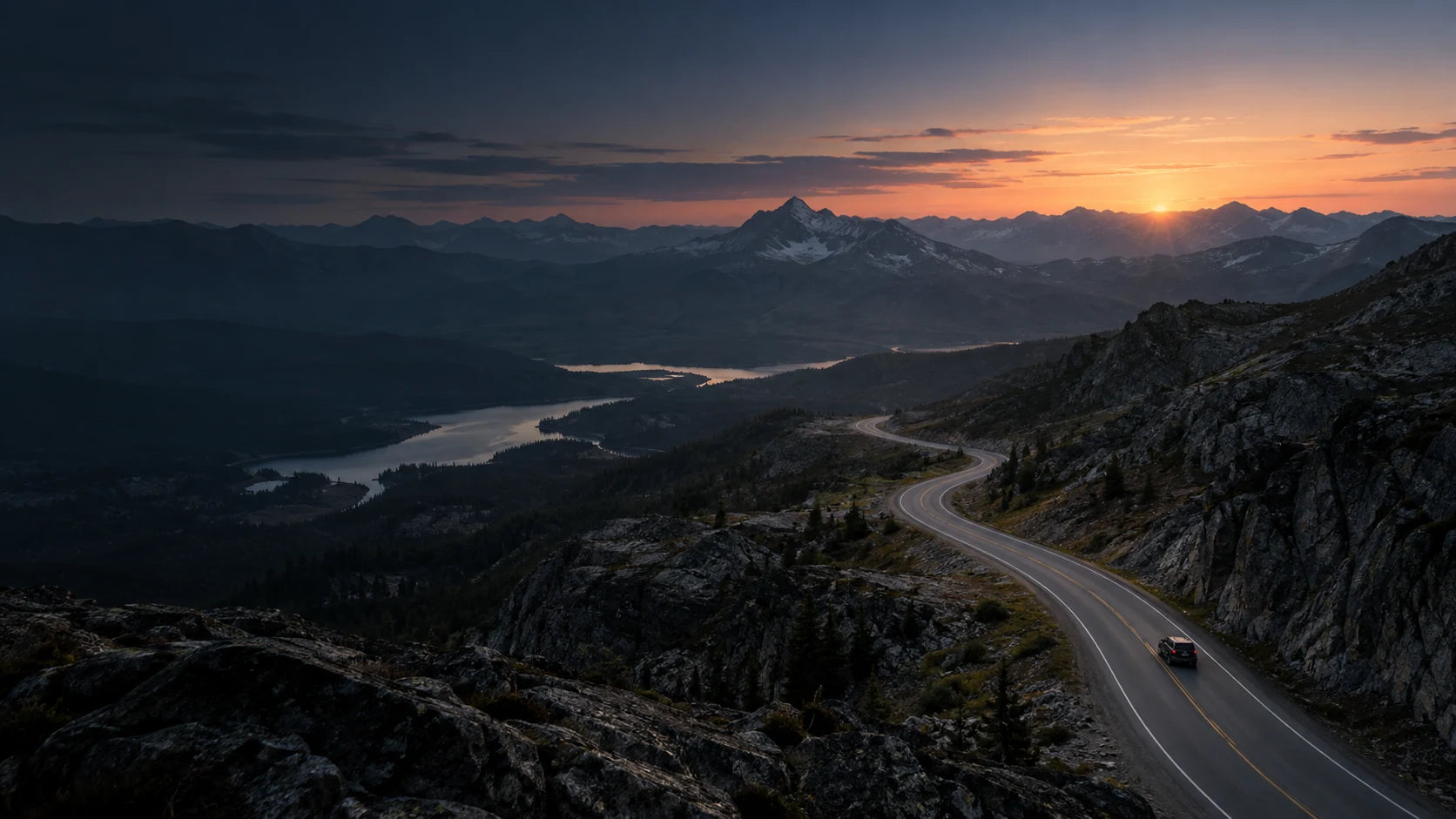 A winding mountain road at dawn with a car in the distance
