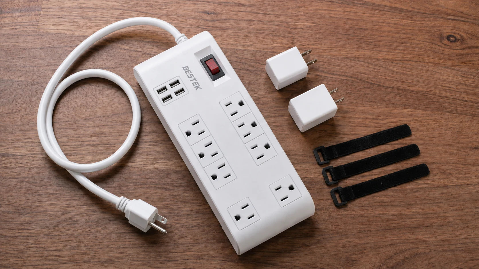 Unplugged eight-outlet strip, two separate plug-in adapters and cable ties arranged on a desk
